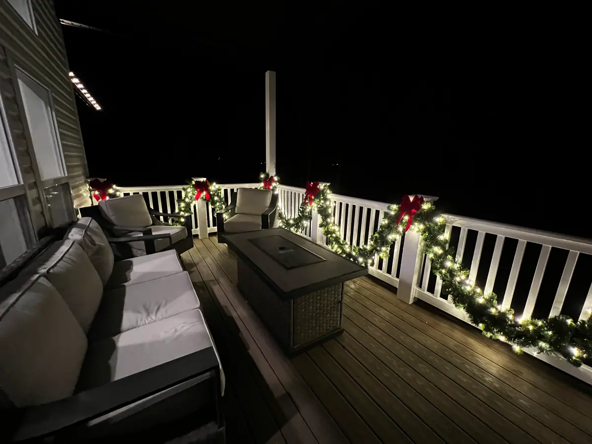 Porch railings wrapped in lit evergreen garland with deep red bows